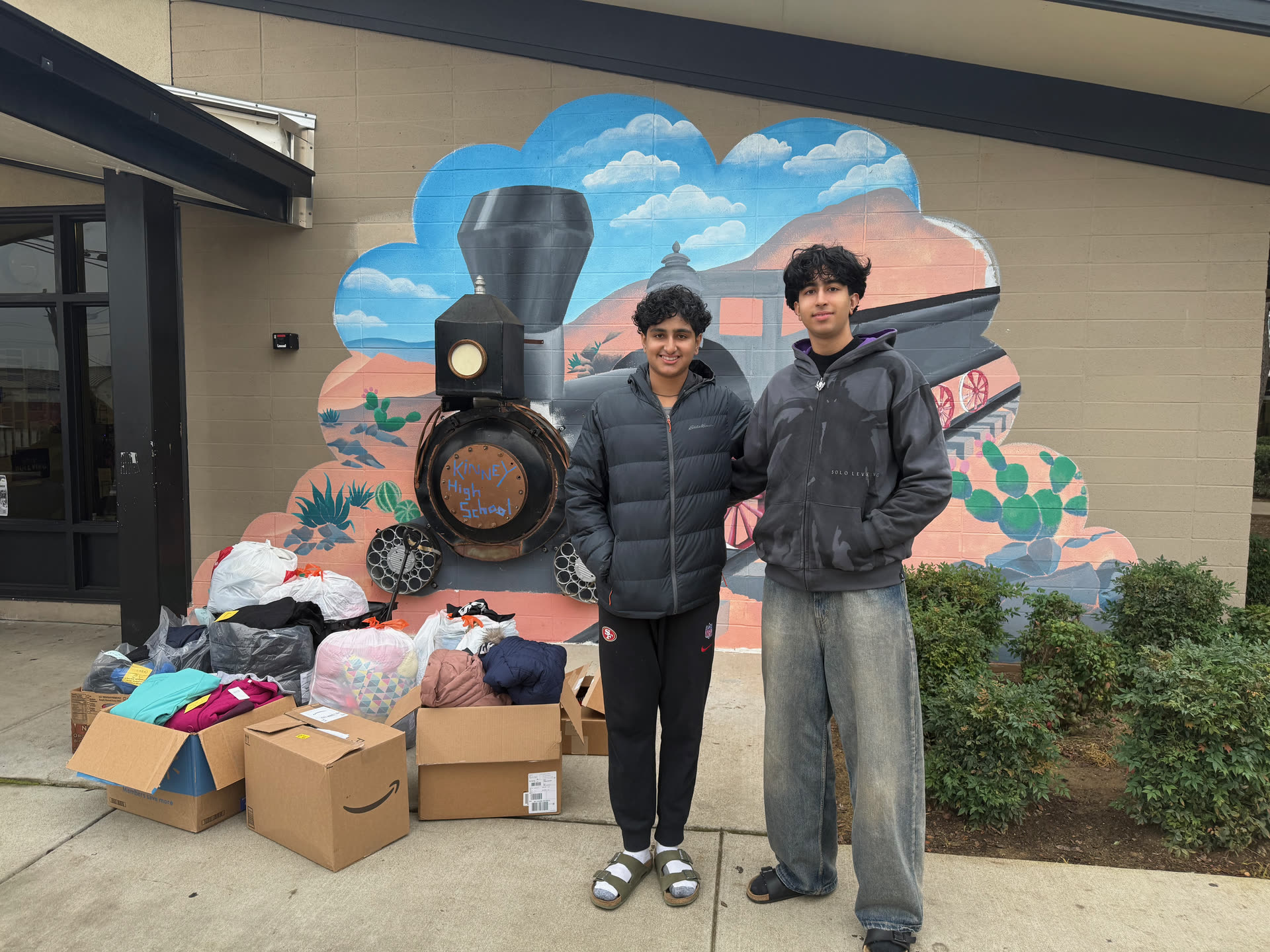 Standing beside boxes of donated clothing outside a community building