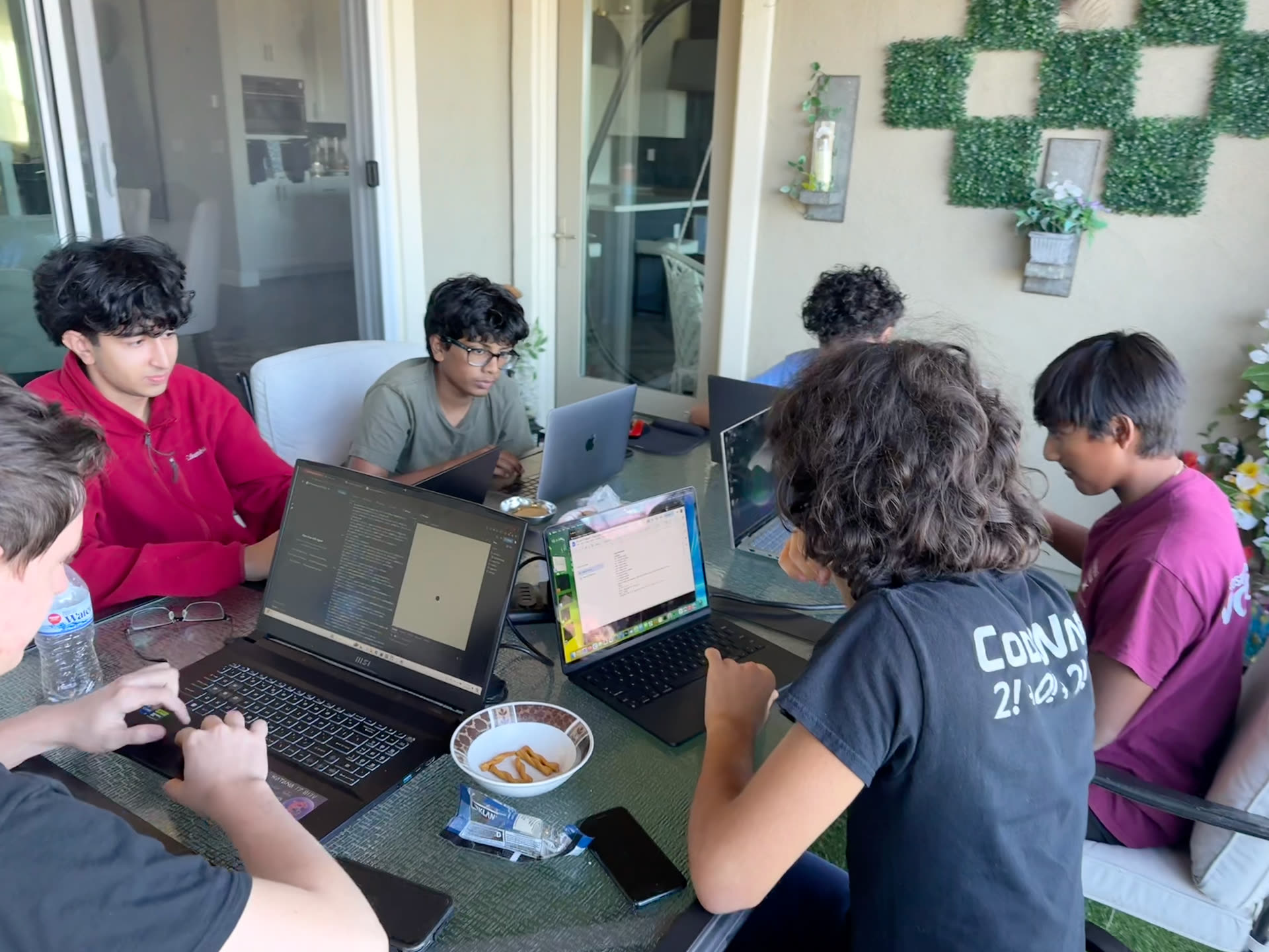 Students working together around a table with laptops